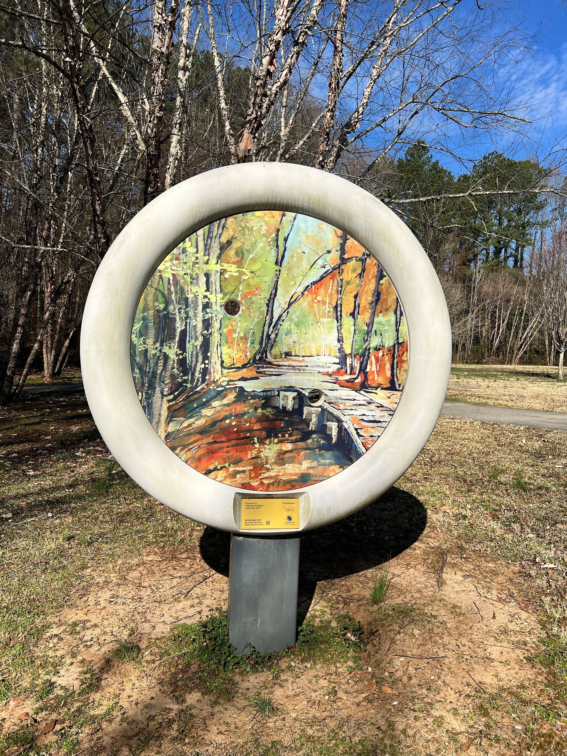 painting of trees and bridge over a creek on a large button sculpture