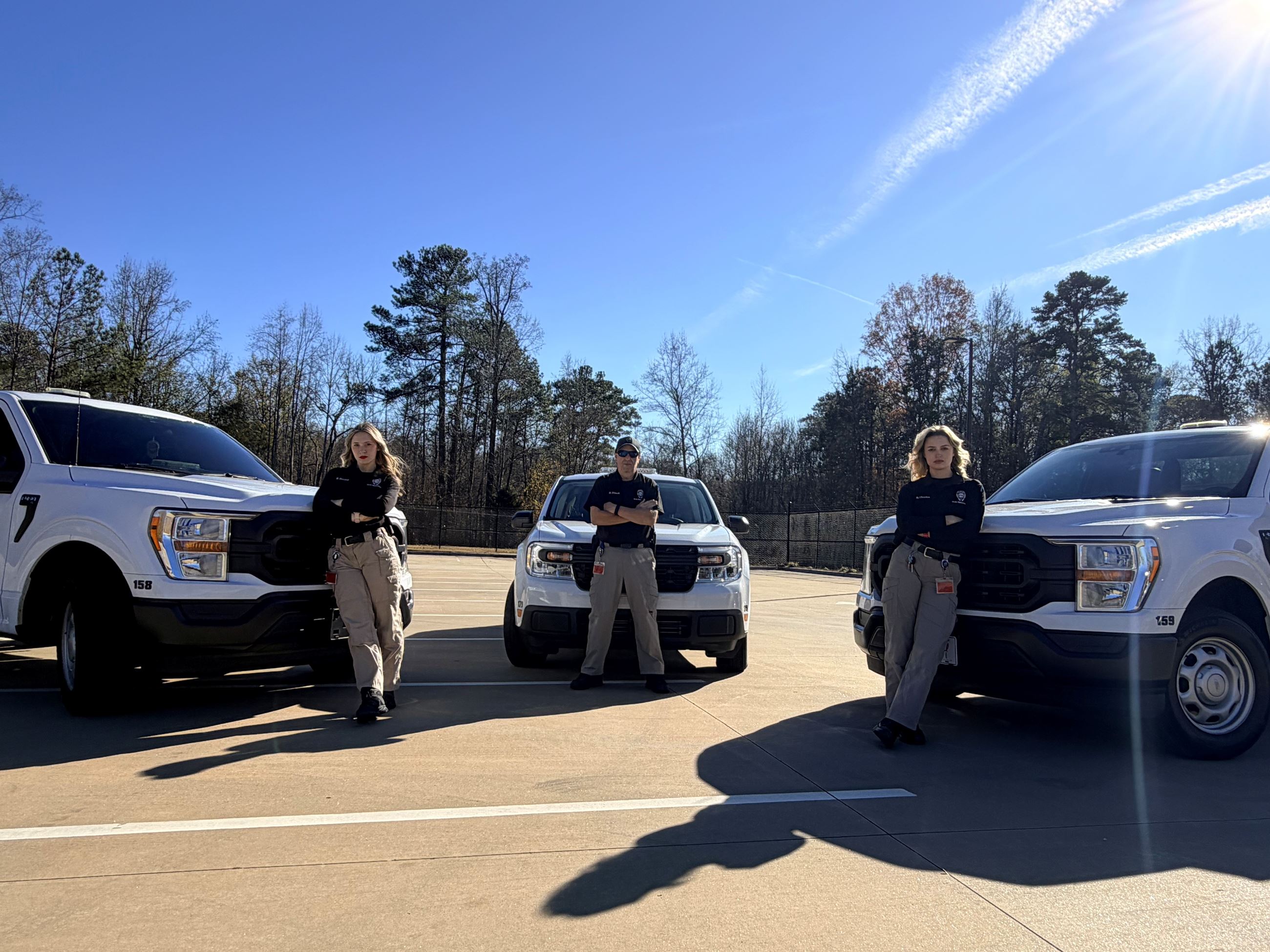 This photo is of three code enforcement officers standing in front of their City of Lilburn trucks.